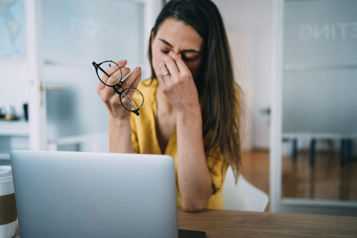 Frustrated businesswoman with head in hands sitting on the desk in the office