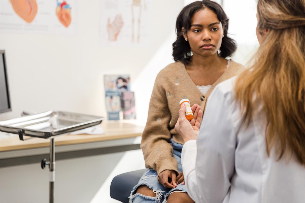 Patient in conversation with doctor holding a prescription