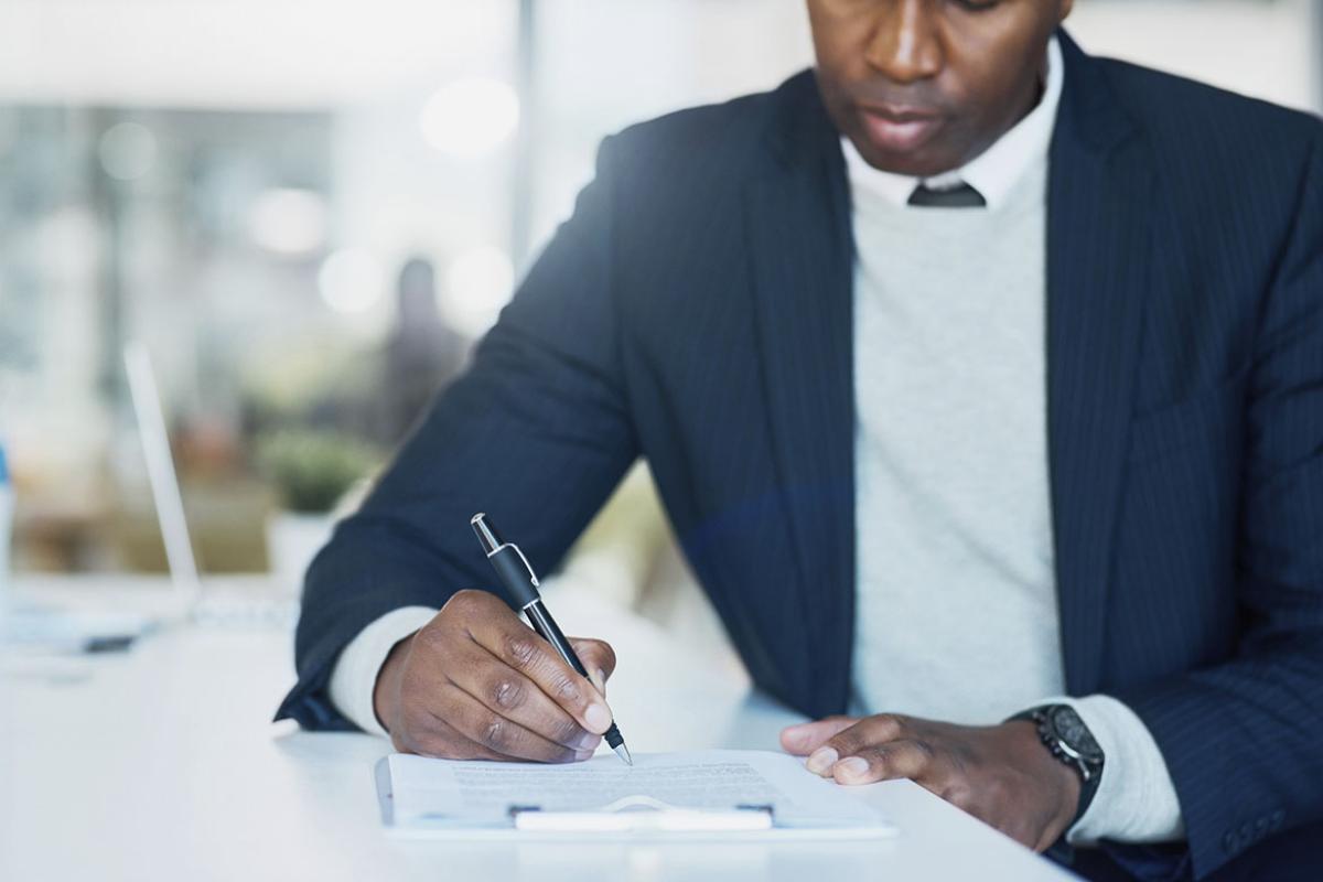 Businessperson filling in paperwork on a clipboard in an office
