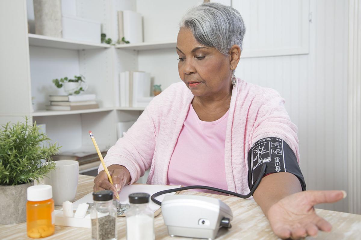 Woman recording her blood pressure at home