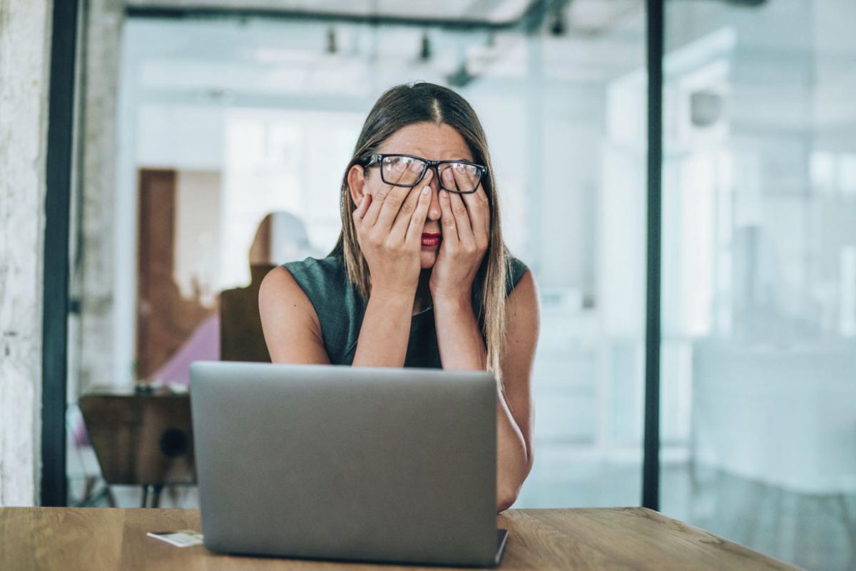 Person at a desk, hands covering face