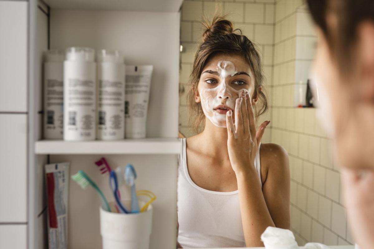 Young woman applying foaming face cleanser in the bathroom