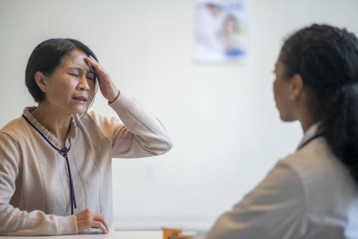 Distressed patient with head on forehead across from a physician