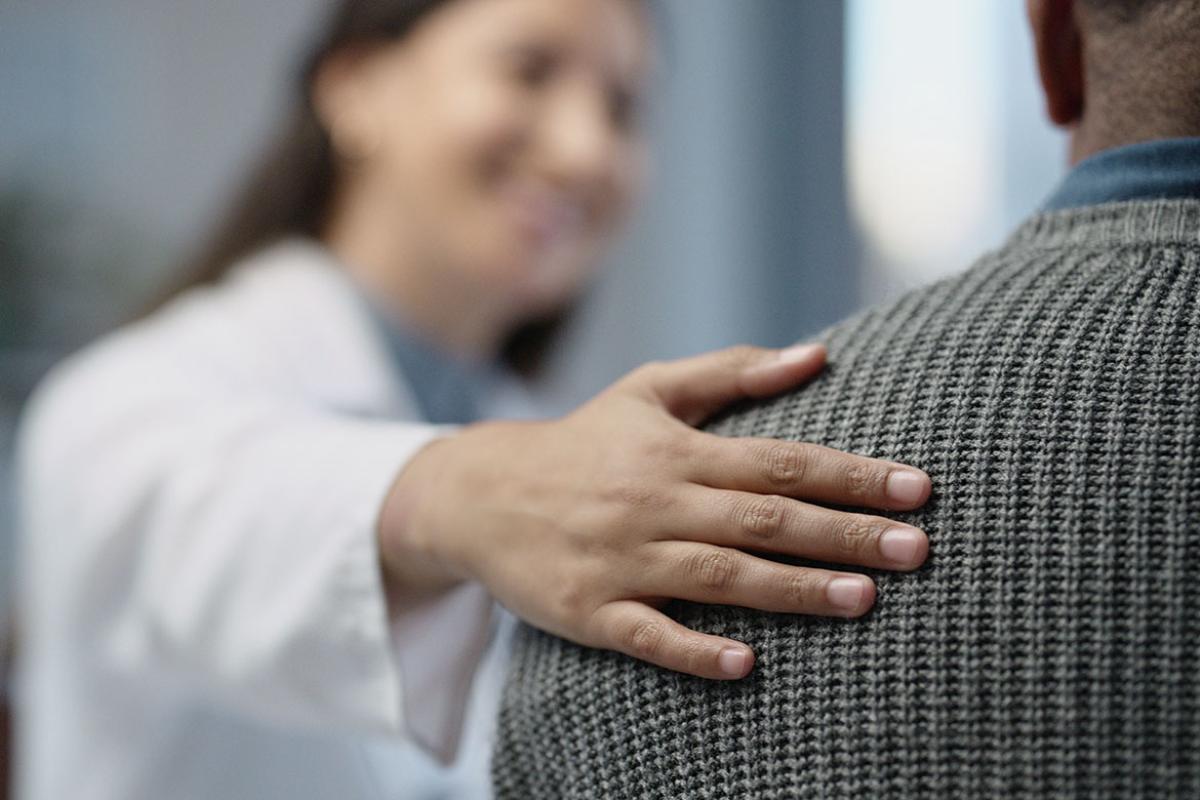 Smiling health care worker with hand on patient's shoulder