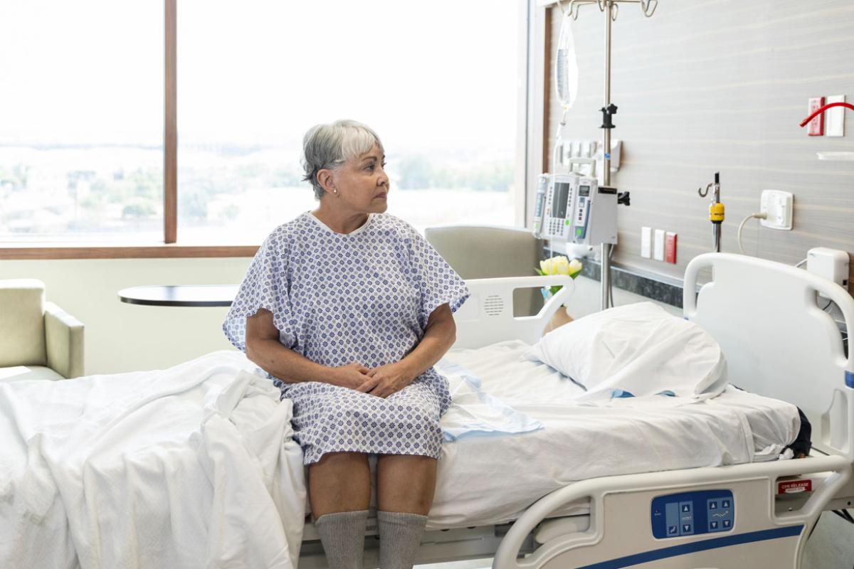 Senior woman sits on side of hospital bed