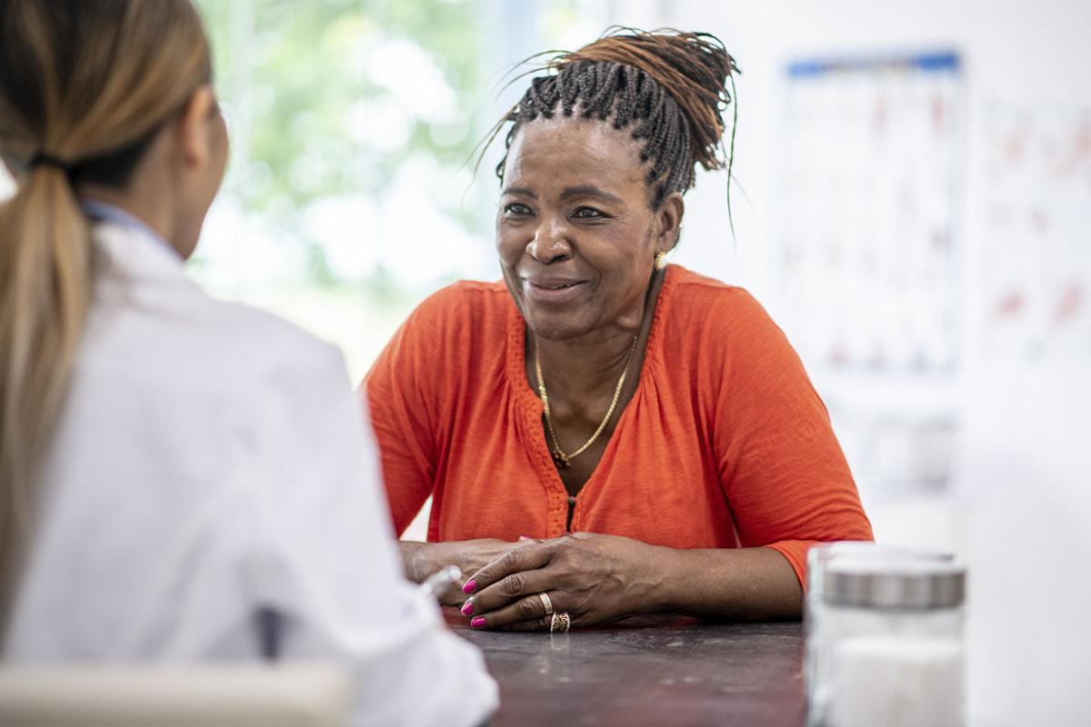Smiling person sits across from doctor