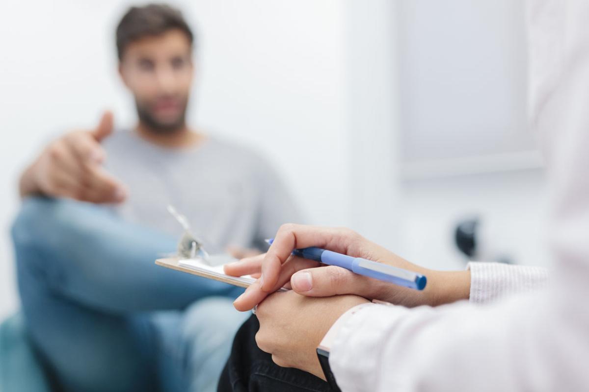 Doctor sitting with note pad while listening to patient
