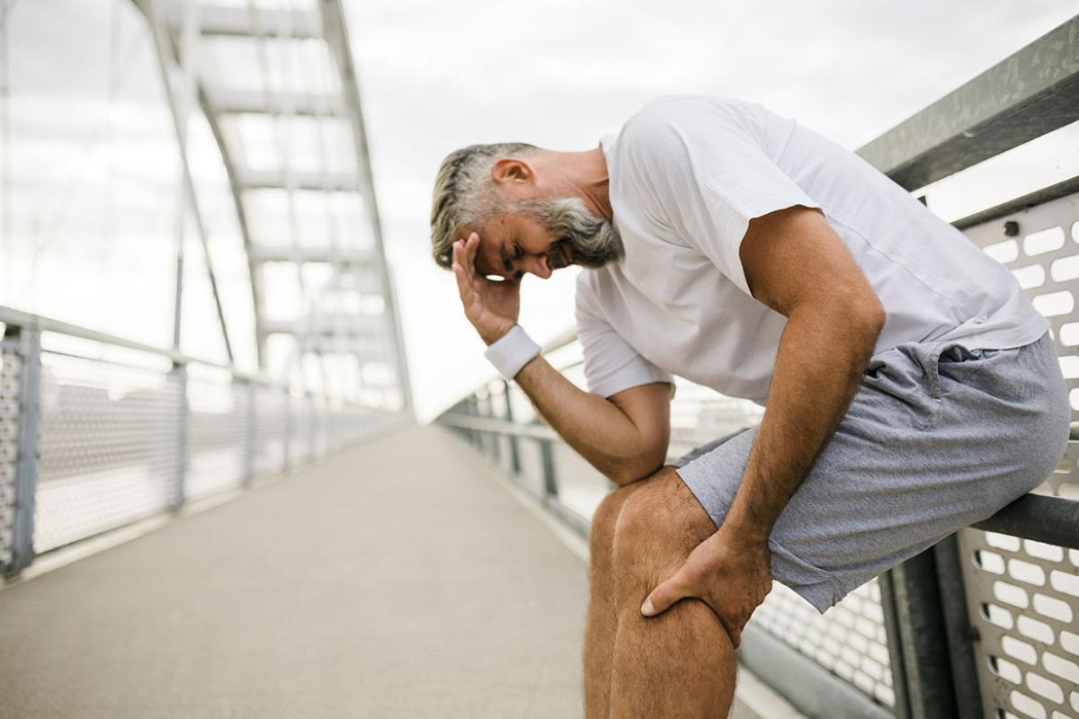 Man in workout gear clenches leg