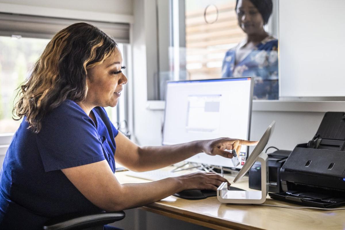 Health care worker accepting payment from patient at reception desk in doctor's office