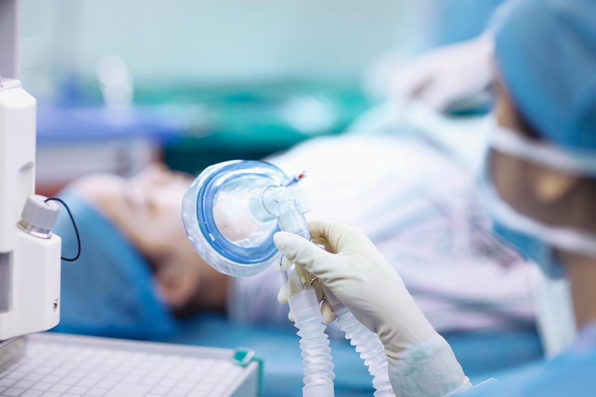 Nurse holding anesthesia mask in operating room