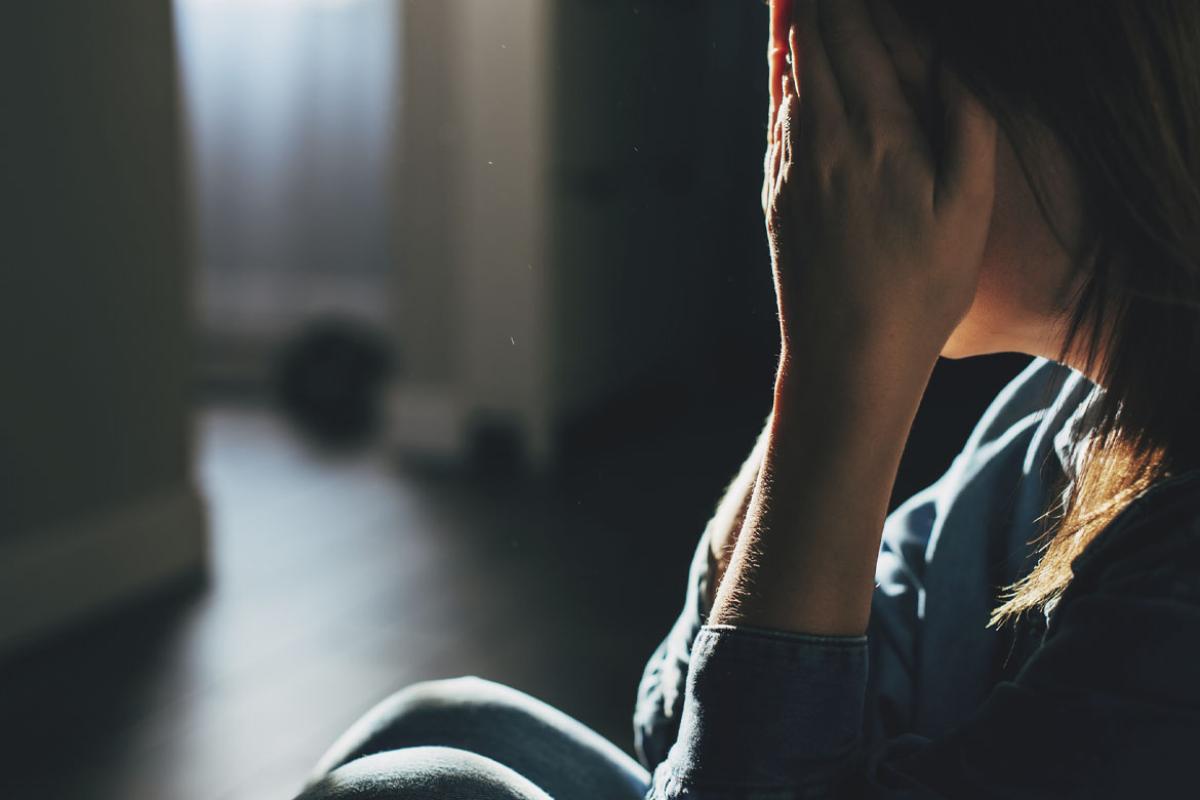 Silhouette of sad person sitting on the floor at home