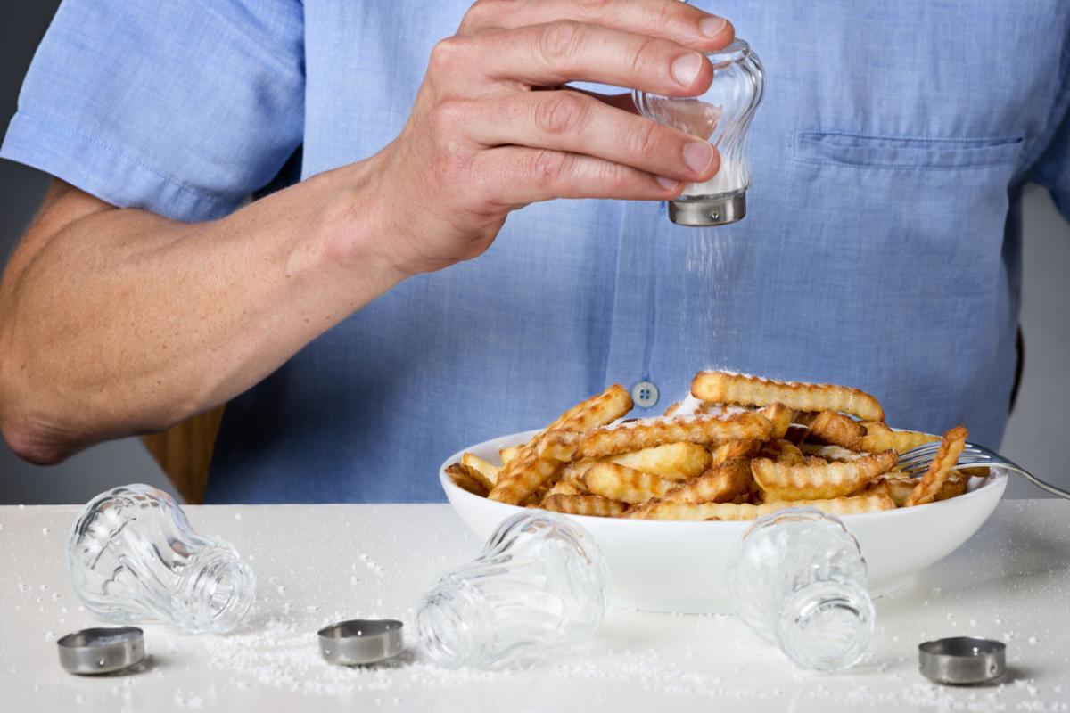 Person over salting a bowl of fries