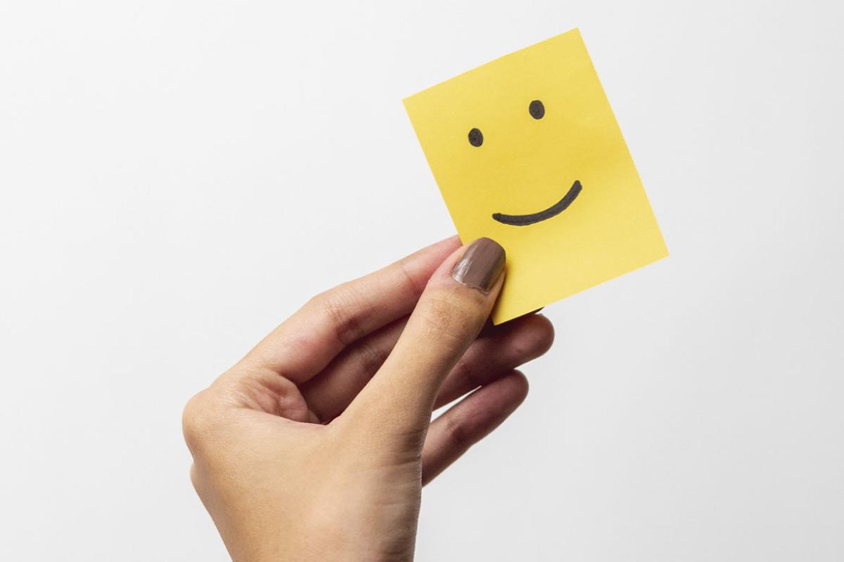 Hand holds a piece of paper with a smiley face