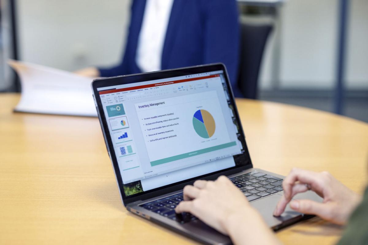 Person preparing business report on a laptop sitting at office