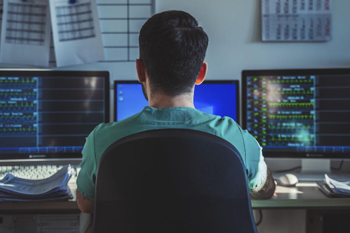 Person works in front of multiple computer monitors