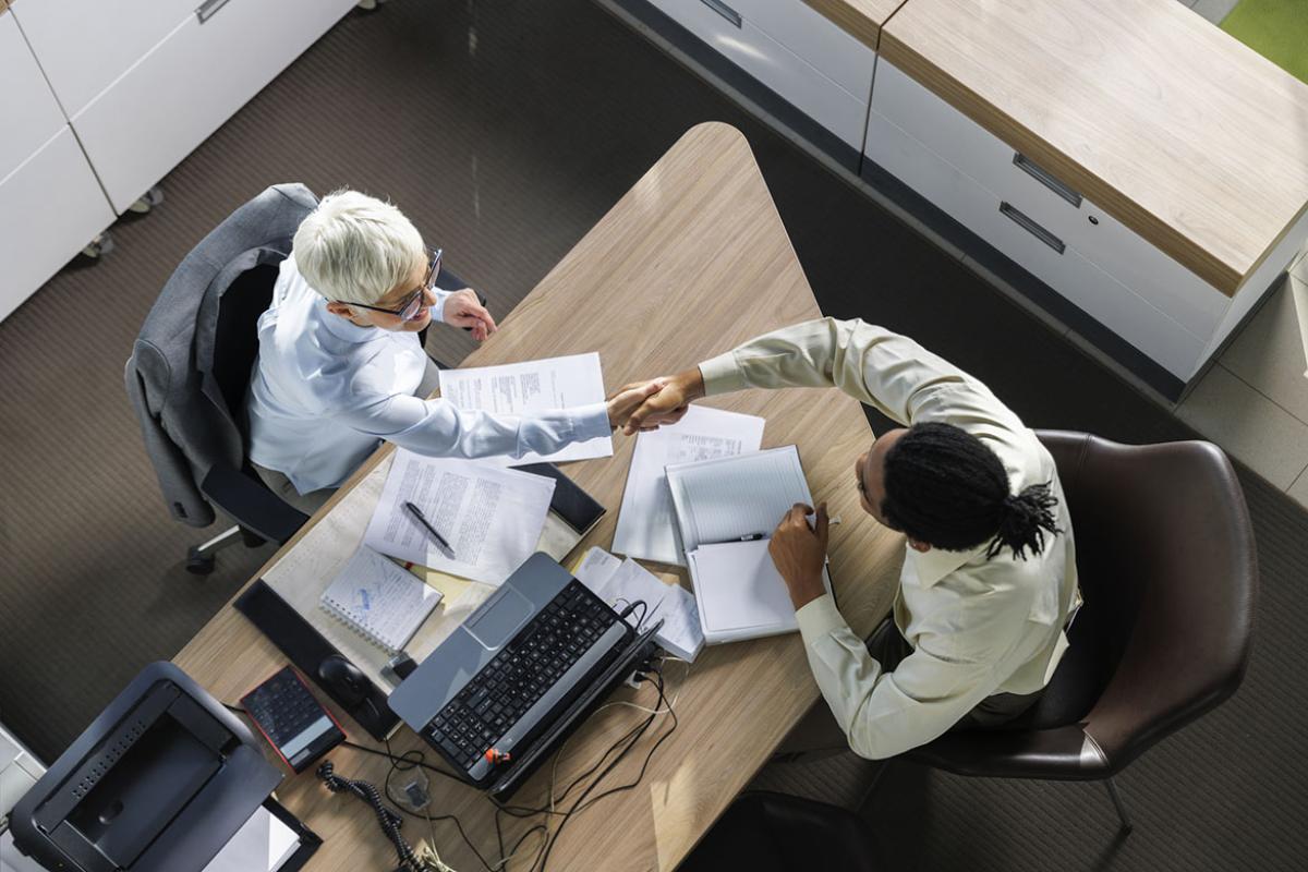 Two people shake hands in an office setting