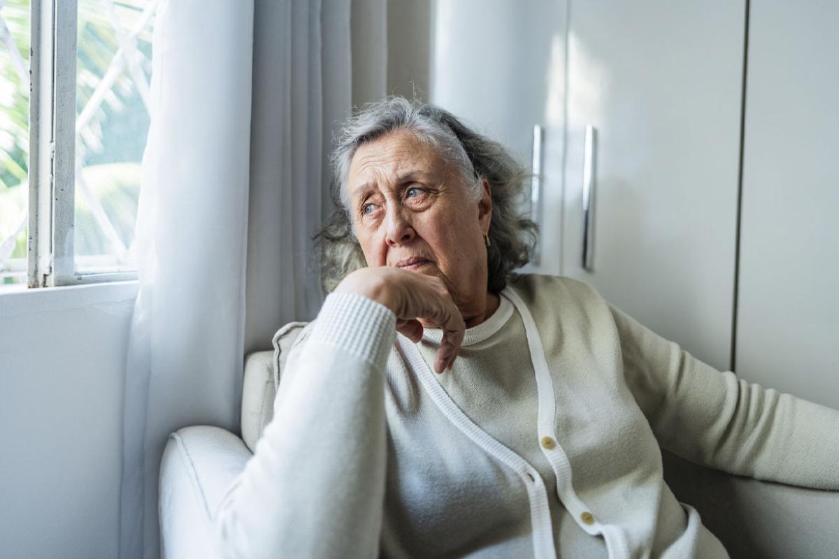 Solemn person looks out a window