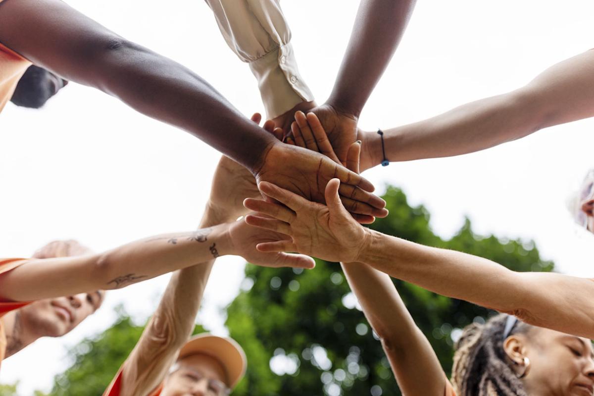 People in circle stacking their hands in the center