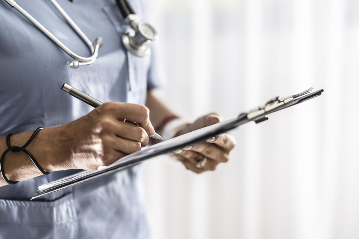 Health care worker fills out a medical form on clipboard