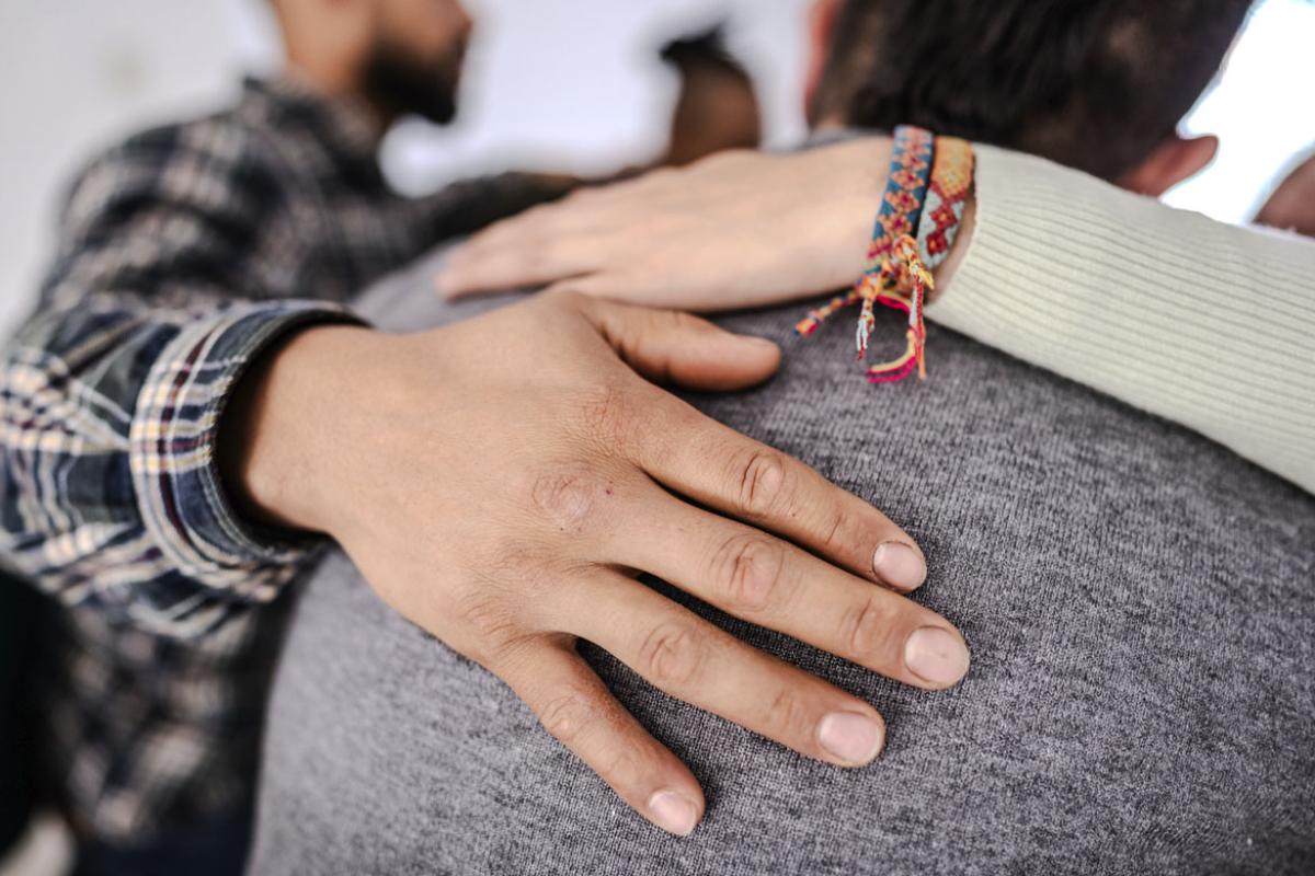 Hand on a shoulder comforting someone during a group therapy session 