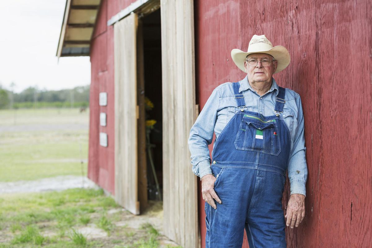 Man leans in front of barn