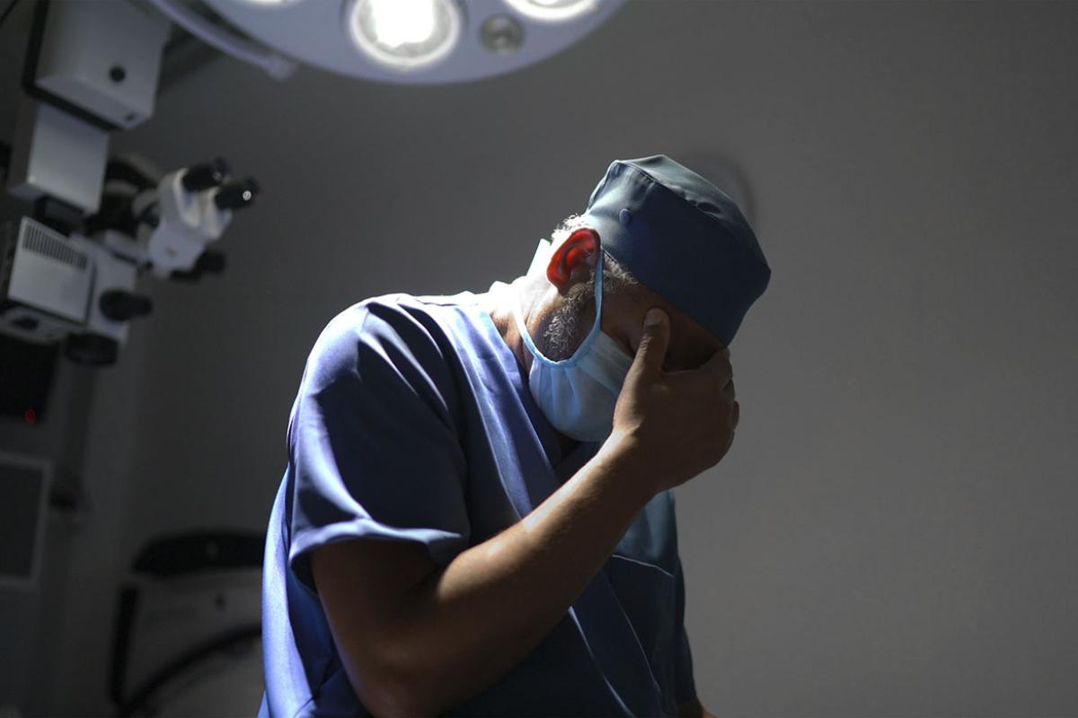 Surgeon with hand on forehead
