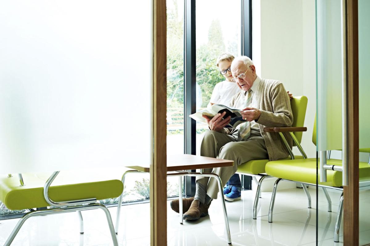 Elderly person reads a magazine in a waiting room