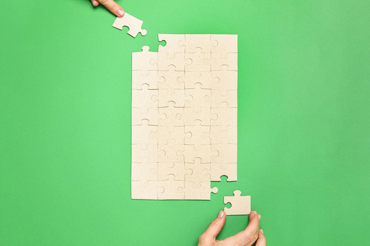 Hands placing puzzle together