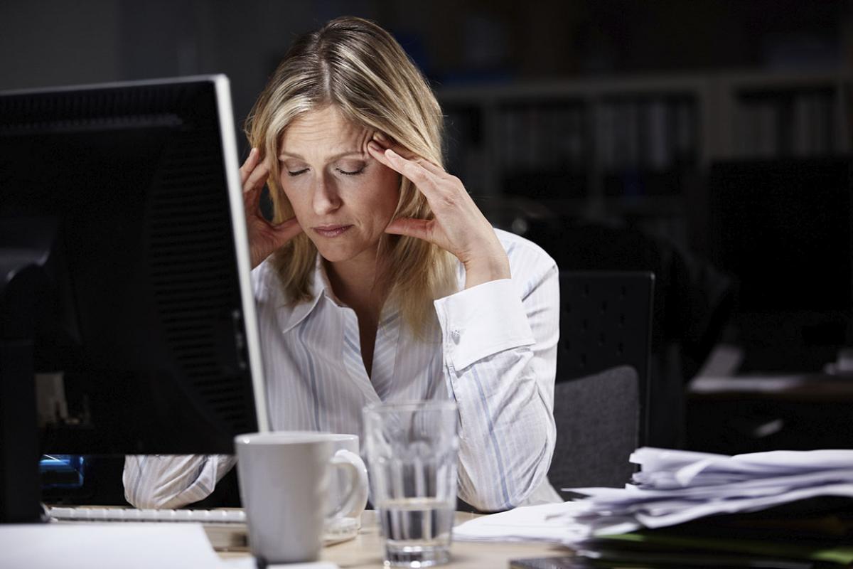 Frustrated person sits in front of computer with head in hand