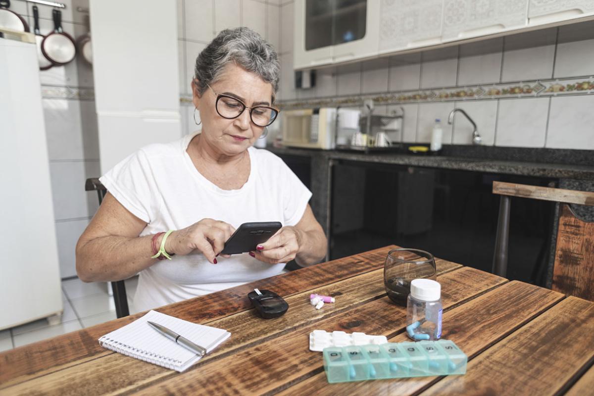 Person recording blood sugar level at home using a smartphone 