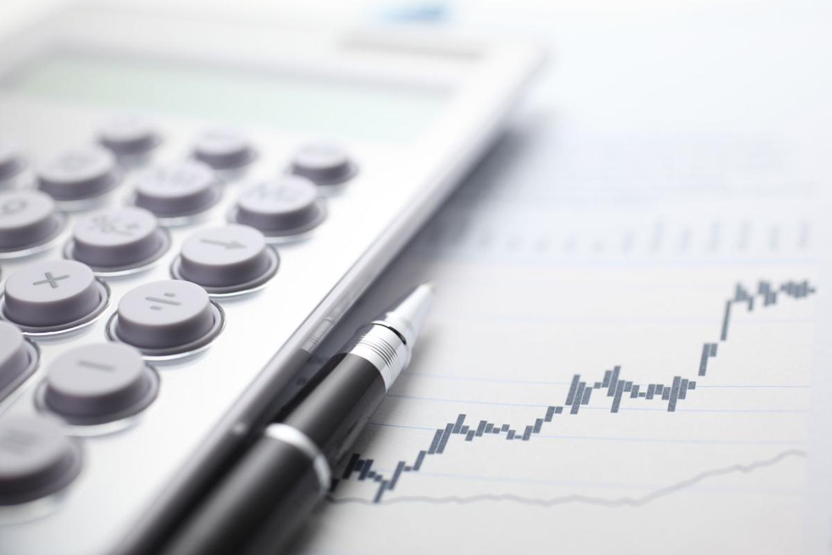 Calculator and ballpoint pen on stock market data chart