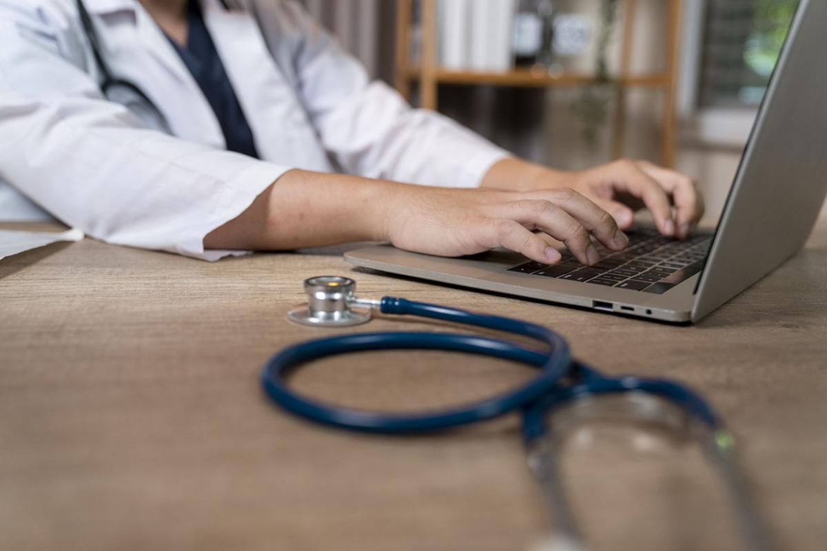 Doctor types on a laptop