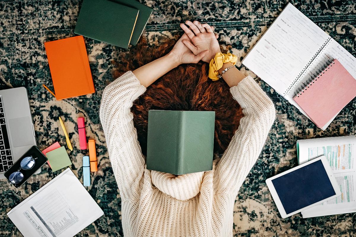 Student laying on the floor surrounded by study items