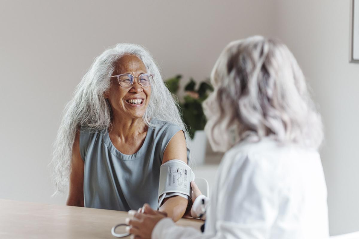 Smiling patient has blood pressure taken by doctor