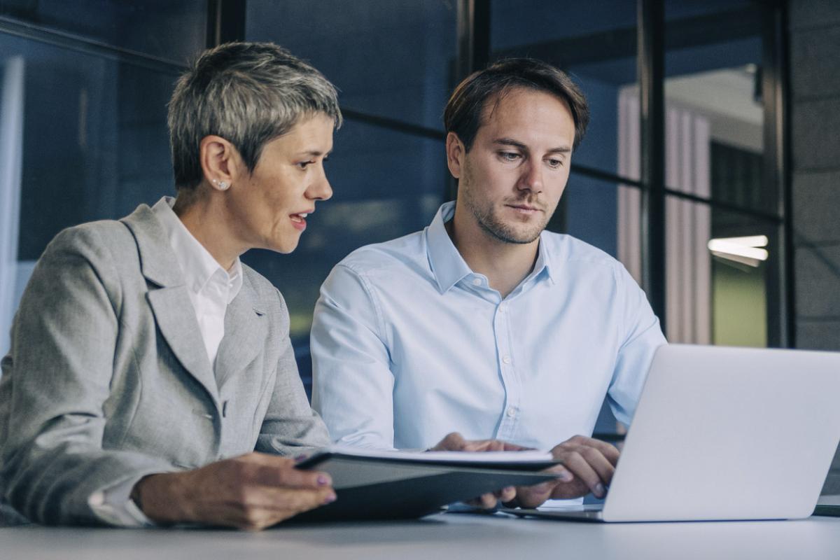 Two colleagues work at a laptop