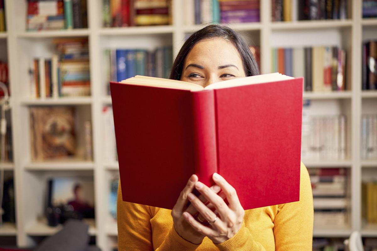 Person holds a book in front of face