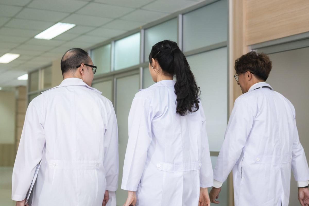 Three physicians walk together in a hallway