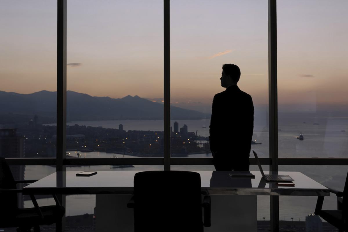 Solitary figure stands in a conference room at dusk