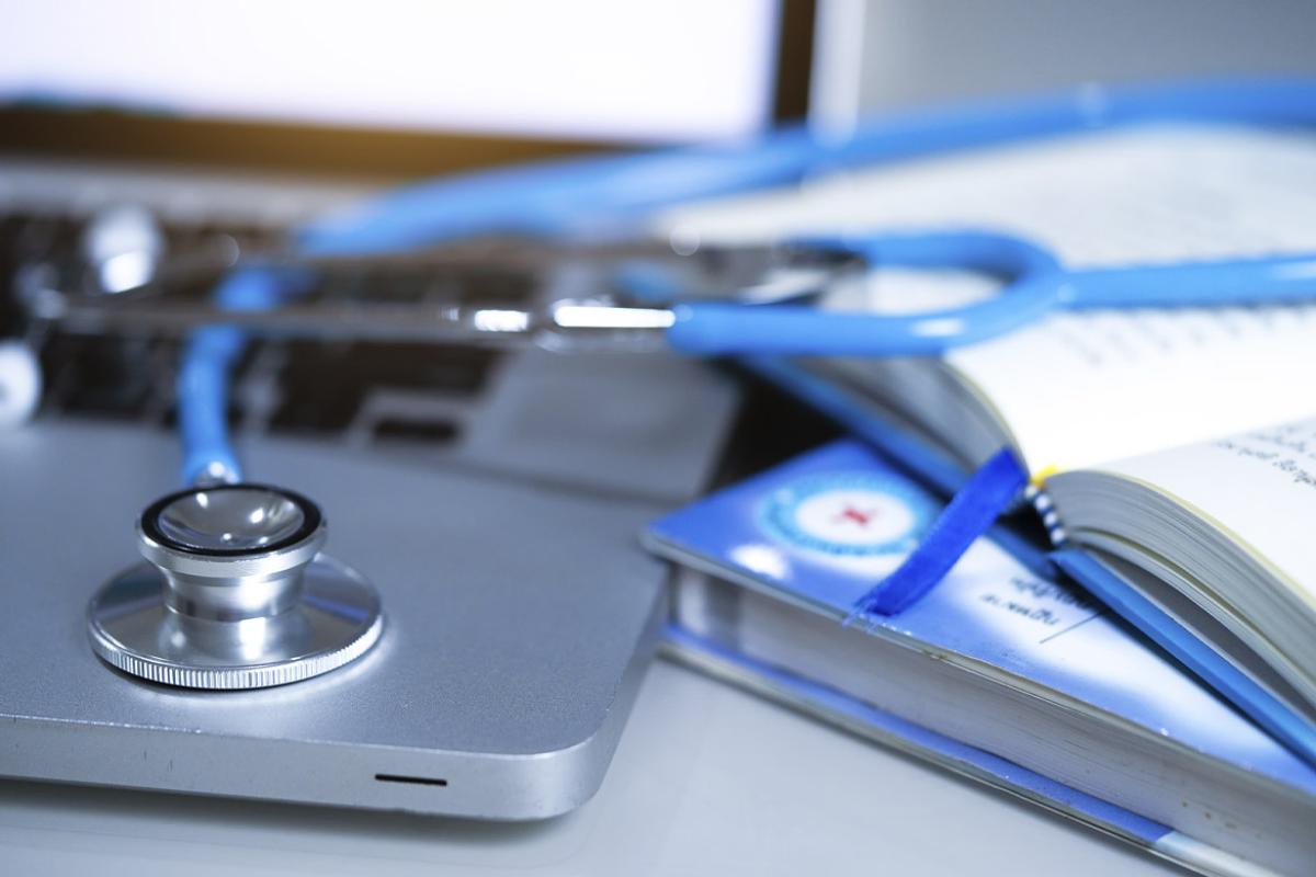 Stethoscope on laptop next to open notebook