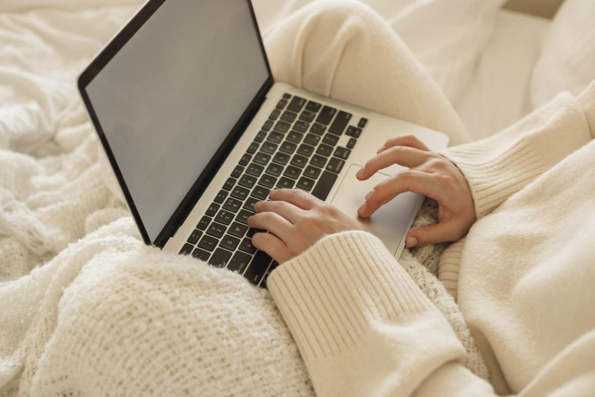 Person in bed works on laptop