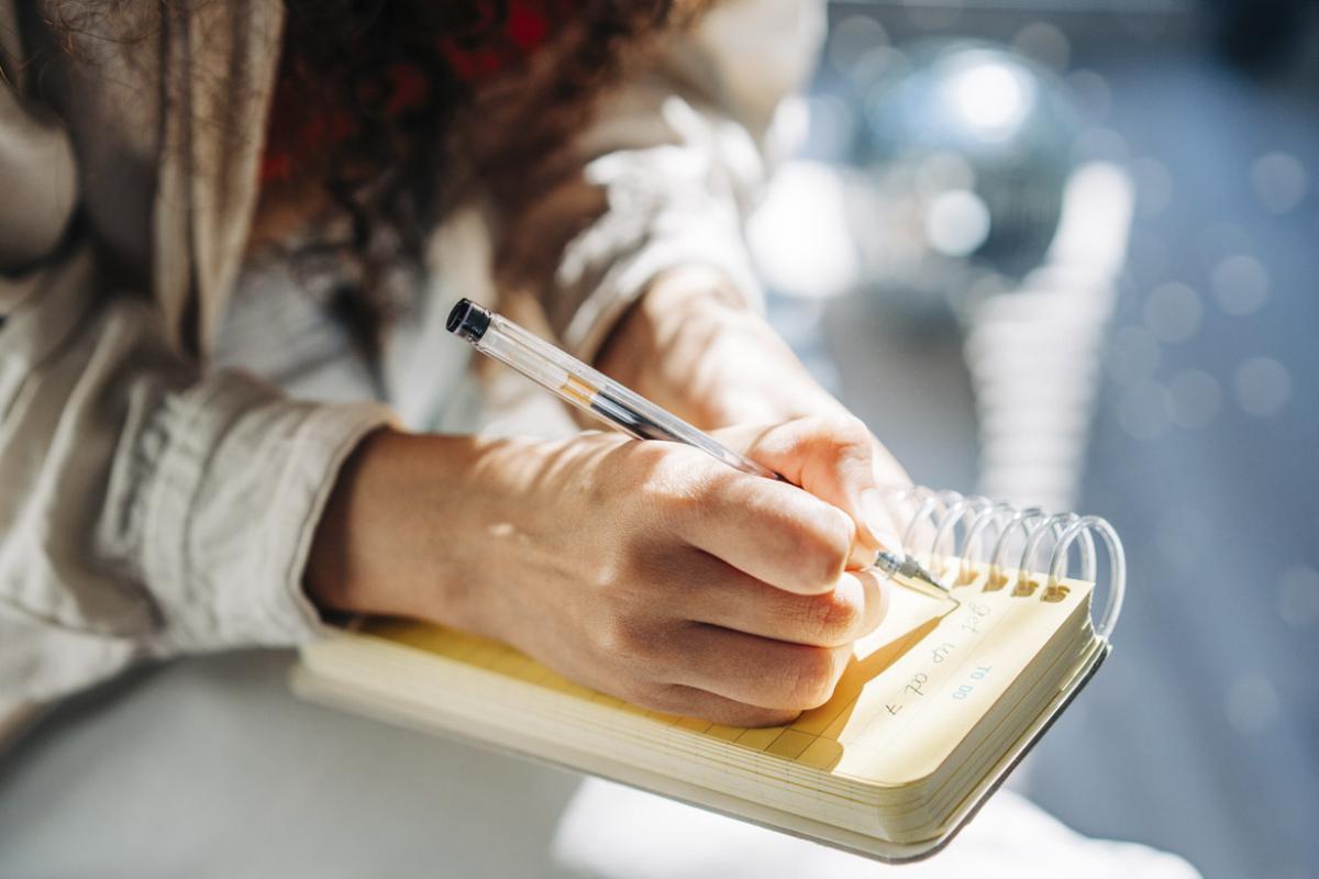 Person writes in a spiral notebook