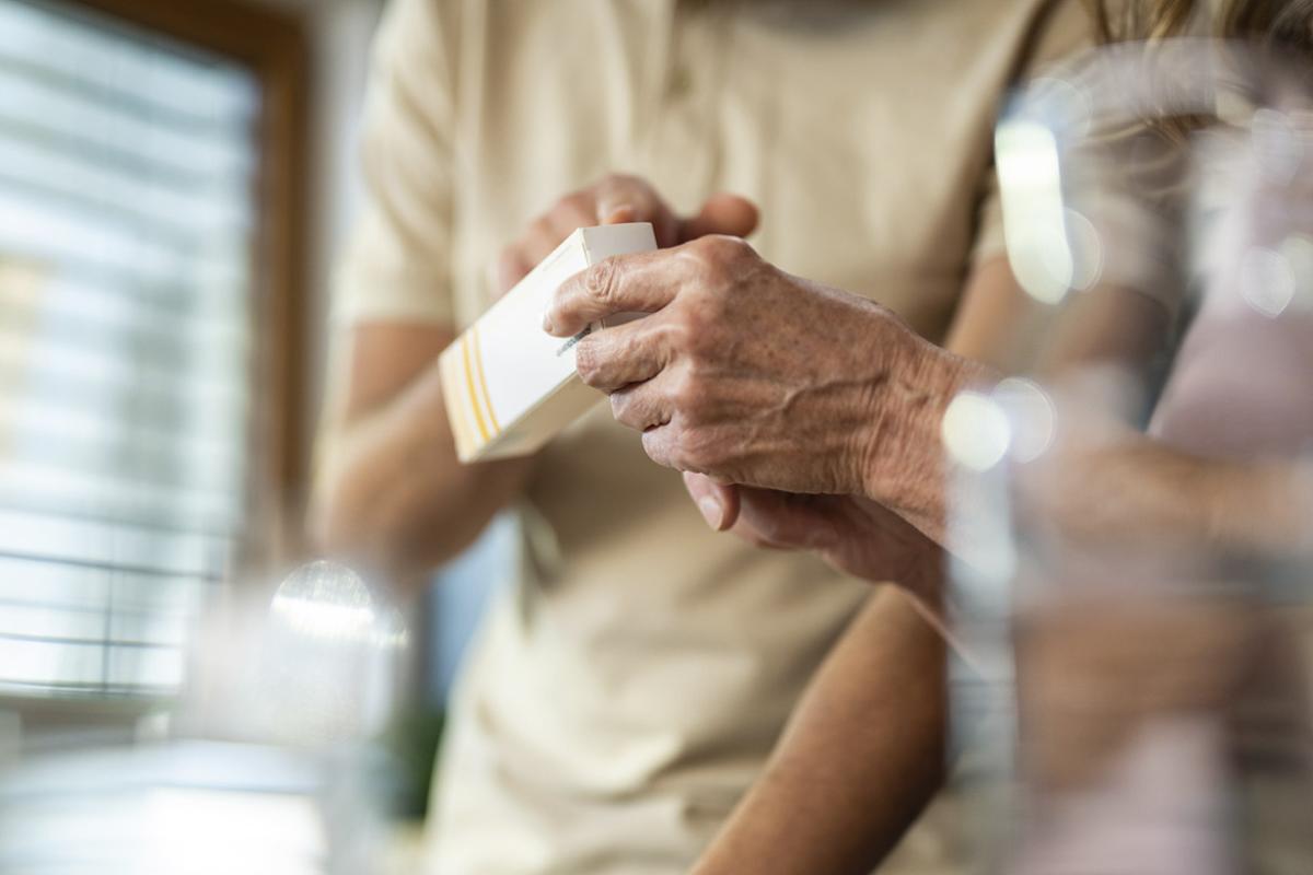 Elderly person holds a box of medication