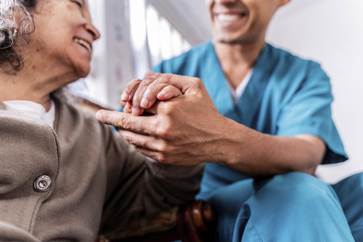 Smiling caregiver holds patient's hand