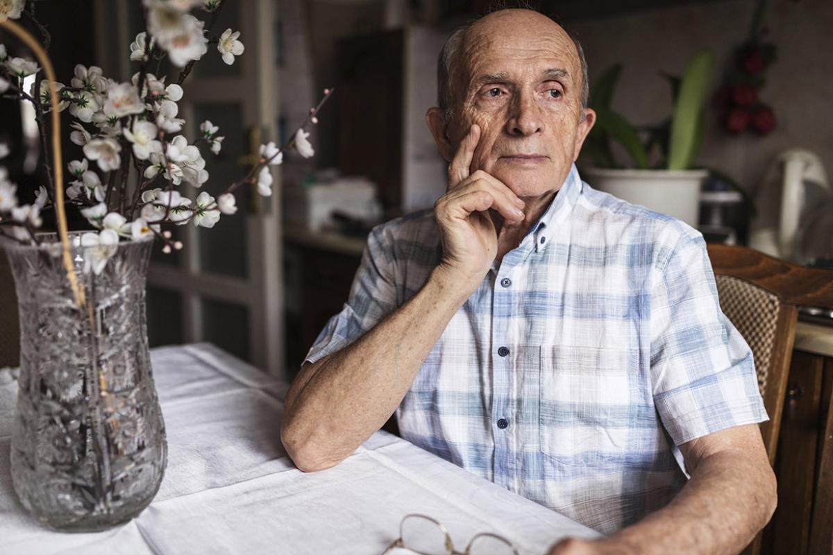 Elderly man sits at a kitchen table
