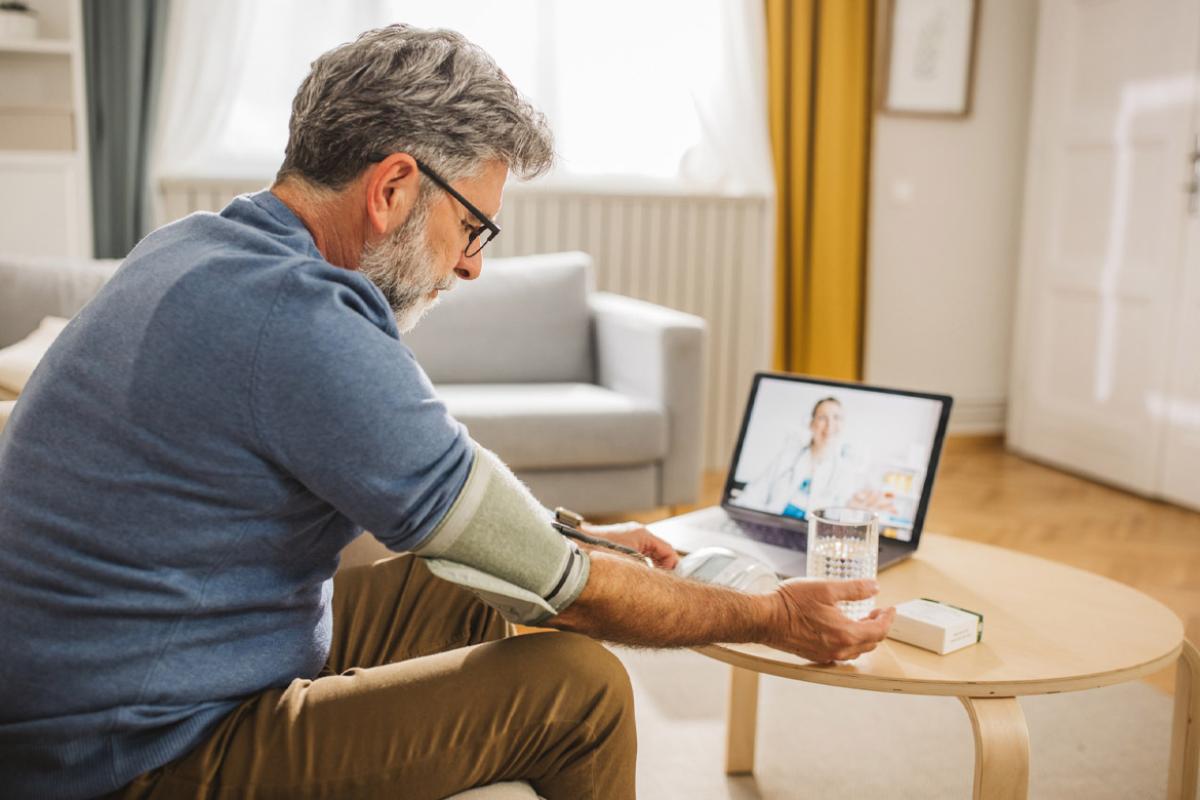 Man using blood pressure cuff during telehealth appointment with physician