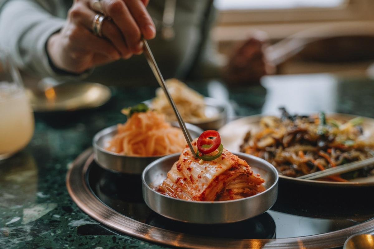Hand holding chopsticks reaches for kimchi