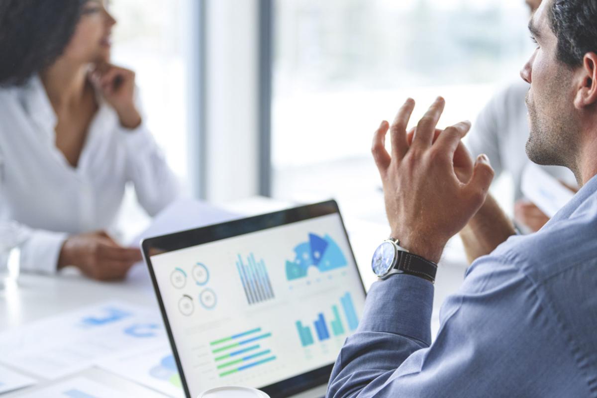 Business person in front of a laptop and document with data and finance charts