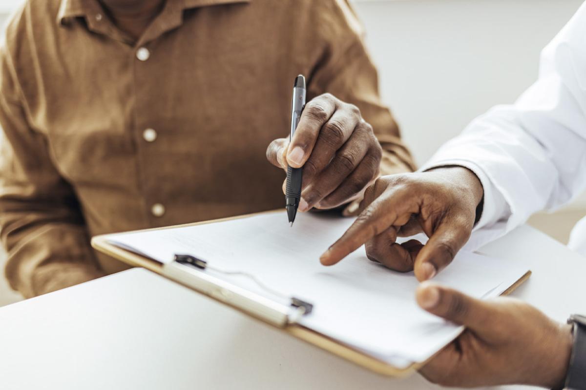Patient's hand poised to sign a document
