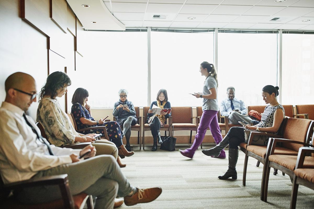 Nurse walking through medical office waiting room to greet patient 