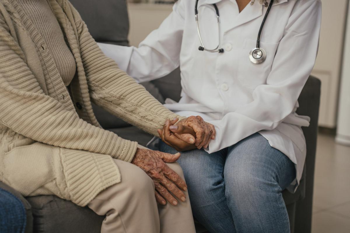 Health care worker comforts to elderly patient at home